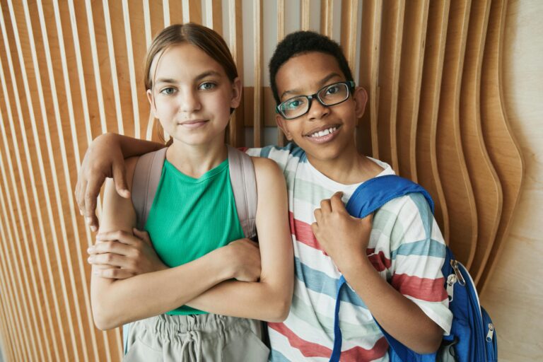 Two diverse teenagers posing with backpacks, symbolizing friendship and school unity.