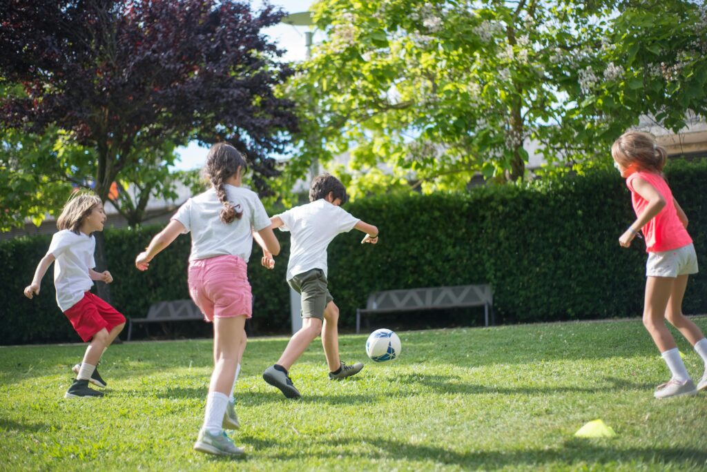 Group of kids enjoying a football game on a sunny day in the park.