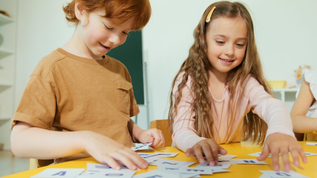 Happy children engaged in learning with educational flashcards in a classroom setting.